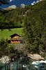 003285_Heuscheune Holzhuschen Foto auf grner Bergwiese ber Bachwasser unter Waldbumen am Hang Naturbild mit Wunspitze Gipfelsicht