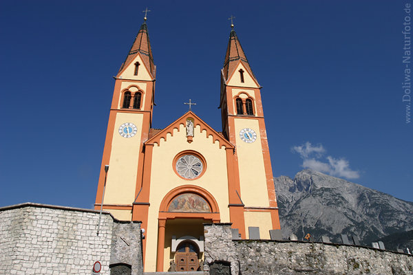 Telfskirche historischer Sakralbau Doppeltrme ber Mauer vor Berg Blauhimmel-Hintergrund