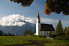 810356_ Tirol Alpen Bergdorf weisses Kirchlein von Msern Herbstfoto, Landschaft an Dorfwiese vor Berg in Wolken