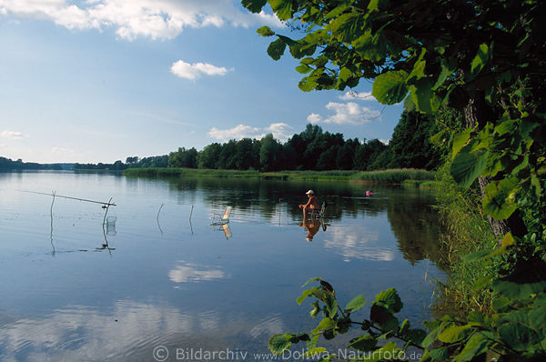 Fisch-Angler sitzt im Wasser Stuhl in See Naturidylle Masurens grne Uferpanorama