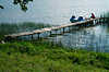 Seeufer-Steg mit Trettboot-Touristen liegen auf Holzsteg Schilf Wasserlandschaft Grnwiese Masuren Seeidylle