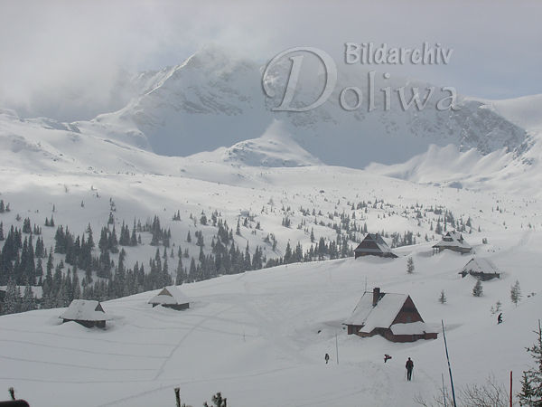 Verschneite Holzhtten im Bergtal Gasienicowa Winter Foto Sennhtten Skilufer im Schneenebel ber Gipfel
