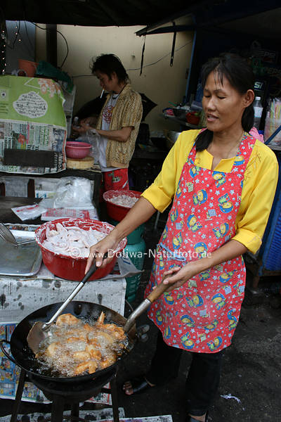 Marktverkuferin bereitet thailndisches Essen gebratene Hhnchenflgel in Pfanne auf Thaiart